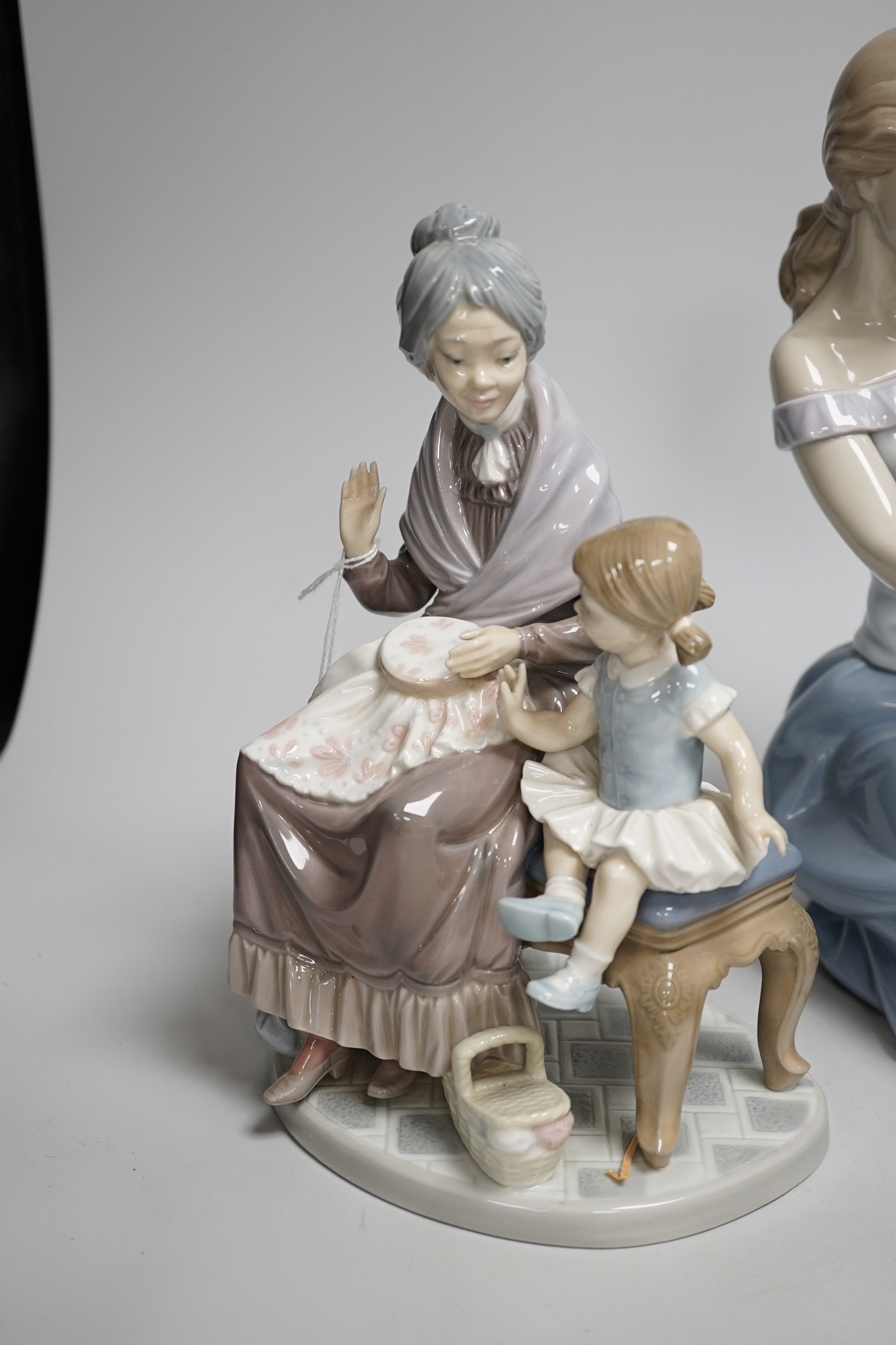 A large Lladro figure of a seated mother and child, a pierrot and ballerina, peasant woman and child, a grandmother and child and two others including a Nao example, the largest 30cm high (6)